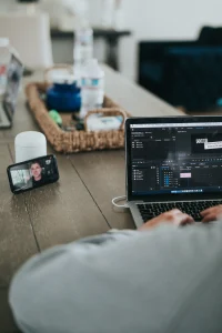 Man editing video on laptop during a video call, multitasking as a micro-influencer or remote content creator.