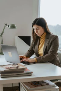 Focused woman working on laptop at home office desk, representing simple online data entry and remote jobs. 