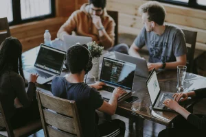 Team of young professionals working on laptops in a modern office, collaborating on tech or software projects.