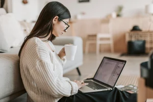Person working on laptop with mug in cozy living room