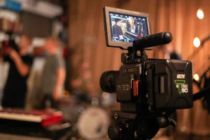 Professional RED camera filming a video shoot with blurred crew and equipment in a studio background
