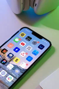 Close-up of smartphone screen with finance, productivity, and AI apps beside wireless headphones