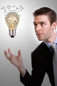 Businessman holding glowing lightbulb with business diagrams and success concepts, symbolizing innovation and strategic ideas